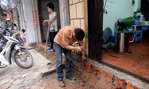 Chủ một cửa hàng kinh doanh trên phố cho biết, anh phải dùng búa và đục để loại bỏ bớt những miếng gạch vữa còn nham nhở trước cửa hàng.