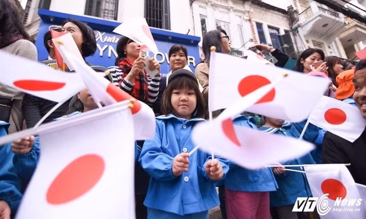 Các học sinh Nhật Bản mang quốc kỳ đón Nhà vua và Hoàng hậu.