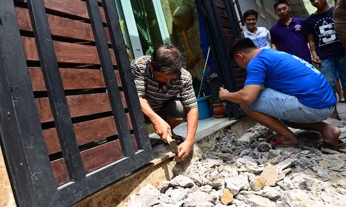 Người dân phụ giúp lực lượng chức năng đập bỏ bậc thềm lấn chiếm trái phép.