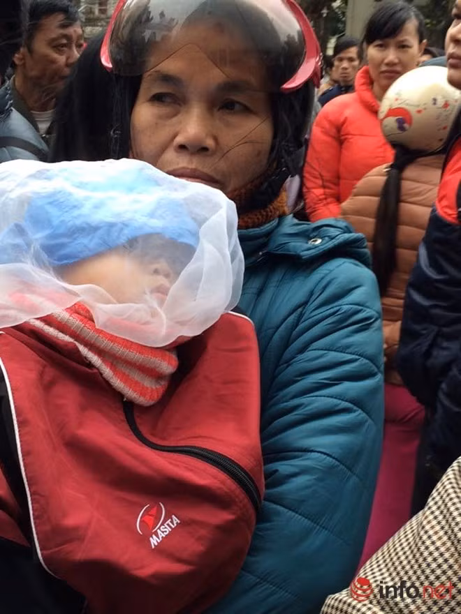 Người dân hỗn loạn trước cửa phòng tiêm. Đứa trẻ ngủ gục trên vai người mẹ trong khi chờ đợi.