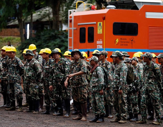 Nhân viên cứu hộ đứng xếp hàng gần cửa hang chờ tiếp vận khi cần thiết. Ảnh: Reuters.