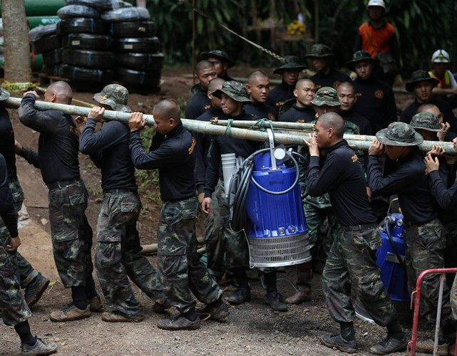 Các binh sỹ cùng nhau khiêng máy bơm nước vào hang Tham Luang. Ảnh: EPA.