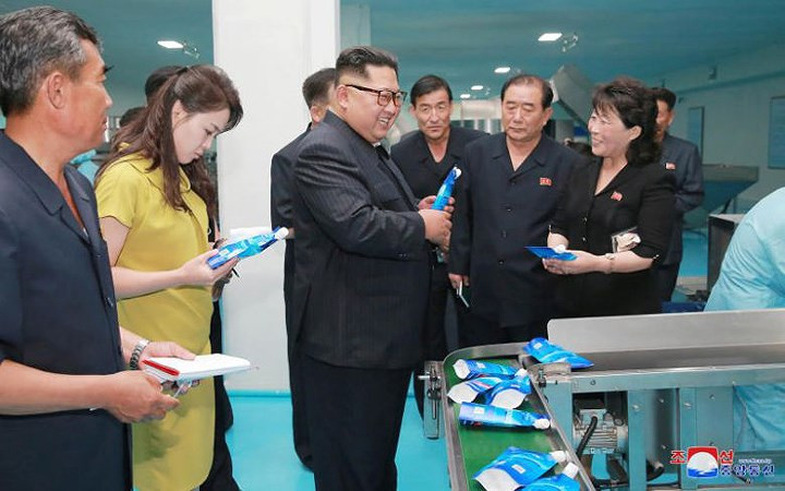 Ông Kim Jong-un (giữa) và phu nhân Ri Sol-ju (trong trang phục vàng) đến thăm nhà máy mỹ phẩm Sinuiju.
