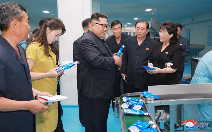 Ông Kim Jong-un (giữa) và phu nhân Ri Sol-ju (trong trang phục vàng) đến thăm nhà máy mỹ phẩm Sinuiju.