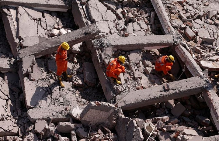 Các nhân viên cứu hộ tìm kiếm những người sống sót trong đống đổ nát của tòa chung cư bị sập. Ảnh: Reuters.