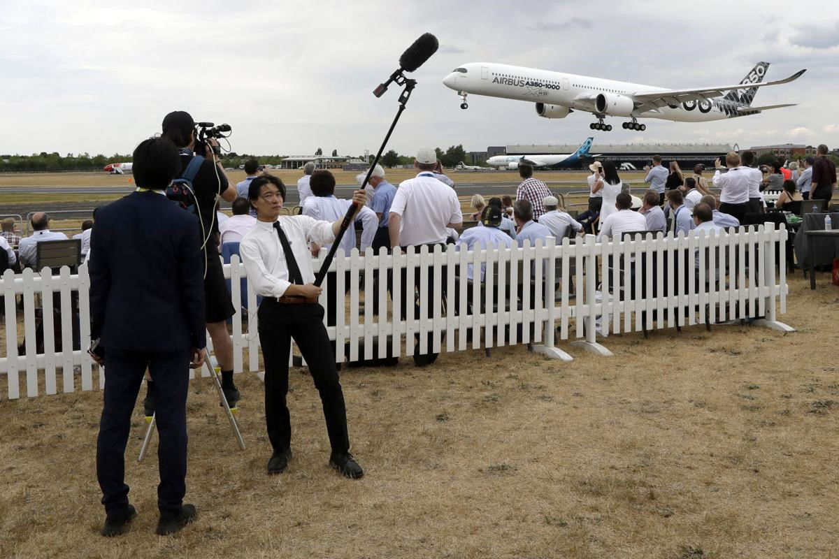 Phóng viên tác nghiệp tại triển lãm Farnborough trong khi máy bay Airbus A350-1000 đang hạ cánh. Chiếc máy bay thương mại này sử dụng hai động cơ của hãng Rolls-Royce Trend XWB, giúp tiết kiệm nhiên liệu, giảm lượng khí thải đến 25% với chi phí bảo dưỡng thấp. Ảnh: AP.