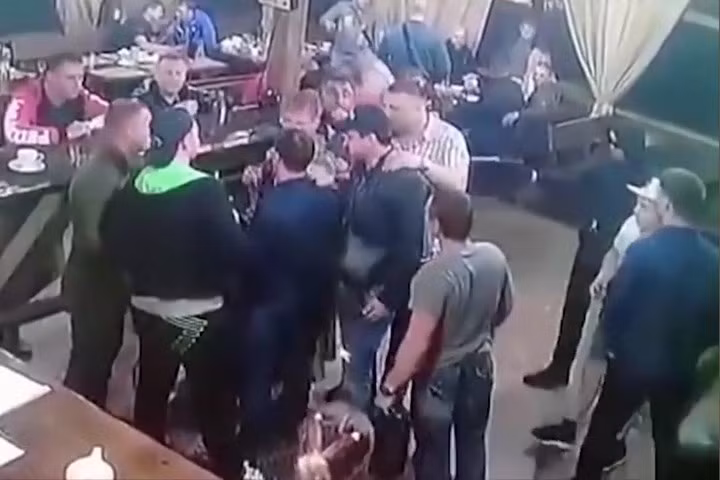 Một sát thủ trùm đầu và đeo kính đen xuất hiện rồi gí súng giảm thanh vào sau lưng Zhestokov. Zhestokov không hề hay biết và vẫn vui vẻ nói chuyện với bạn bè.