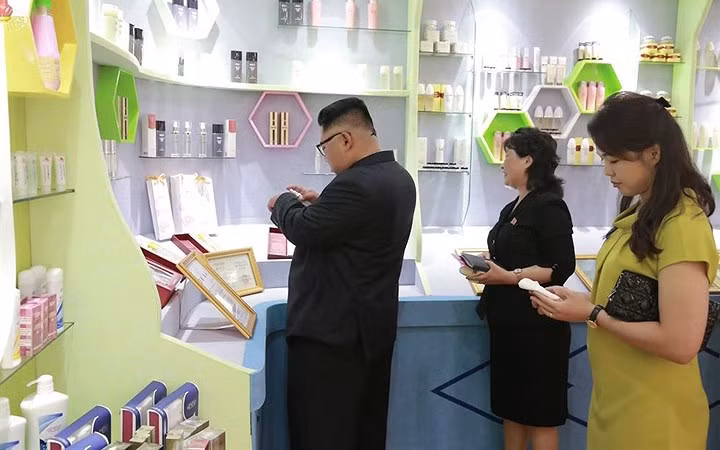 Ông Kim Jong-un thử mỹ phẩm của nhà máy sản xuất lên tay.