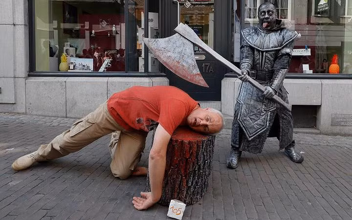 Một du khách đùa nghịch với bức “tượng sống” mang tên “Đao phủ”.