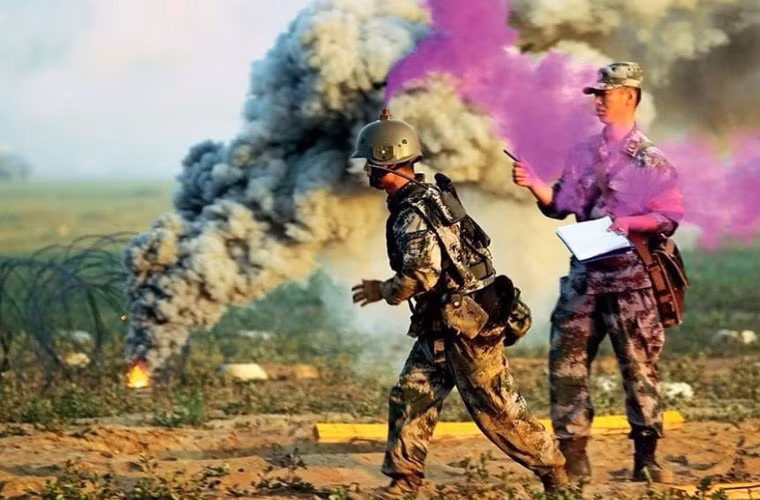 Đây thực ra chỉ là một trong hàng trăm cuộc tập trận mà Quân đội Trung Quốc tiến hành khắp nơi trong tuần. Tuy nhiên, điểm lạ ở đây là các binh sĩ tham gia tập trận đội một chiếc mũ bảo vệ rất kỳ quái, nó có thể phun ra khói màu.