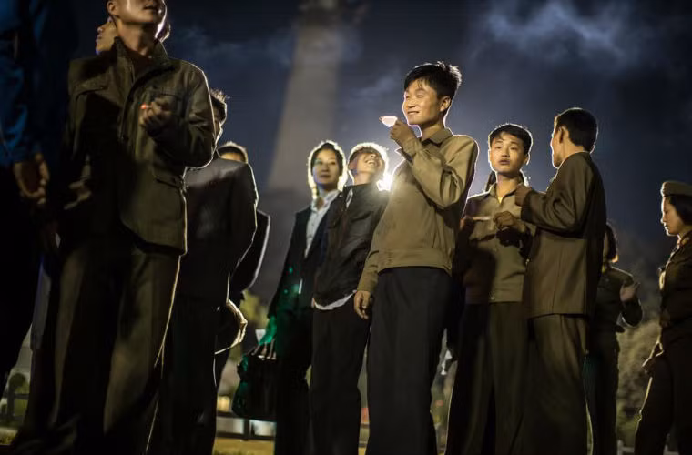 Người đàn ông ăn kem nhập khẩu từ nước ngoài trong khi chờ đến lượt đi xe trong công viên giải trí.