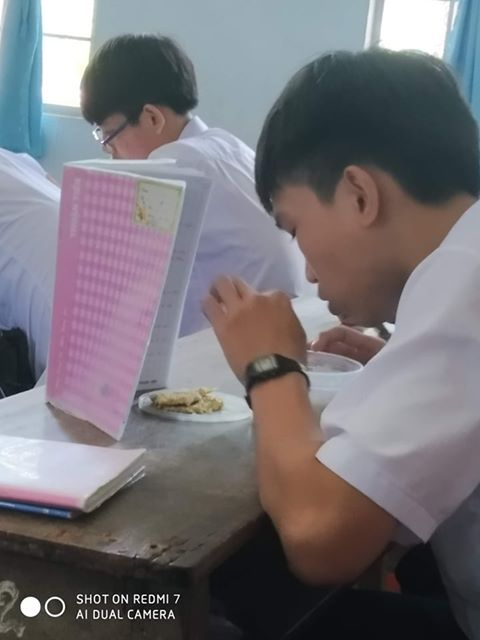 Một nam sinh khác to gan lớn mật ăn vụng trong lớp, cậu đã khéo léo dựng cao cuốn vở lên để che đi màn ăn vụng trong lớp học của mình.