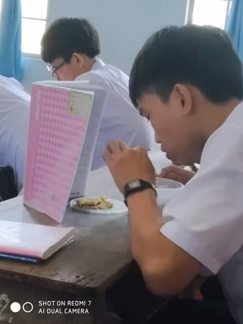 Một nam sinh khác to gan lớn mật ăn vụng trong lớp, cậu đã khéo léo dựng cao cuốn vở lên để che đi màn ăn vụng trong lớp học của mình.