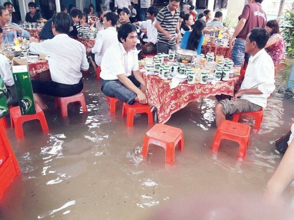 Nước lũ dù dâng cao nhưng quan khách vẫn vui vẻ ngồi đàm đạo bên bàn tiệc cưới.