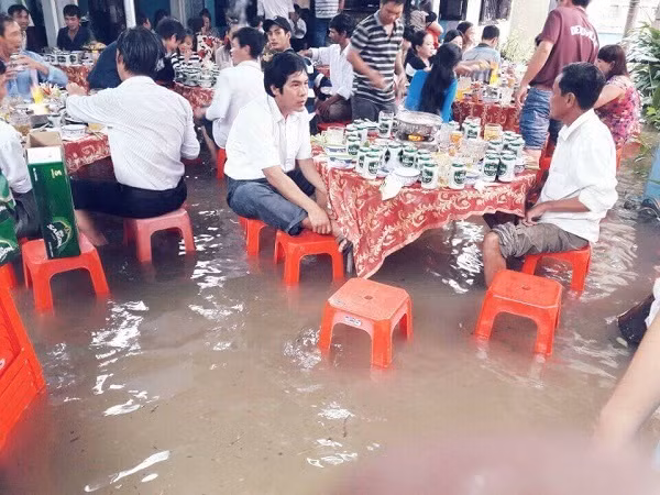Nước lũ dù dâng cao nhưng quan khách vẫn vui vẻ ngồi đàm đạo bên bàn tiệc cưới.