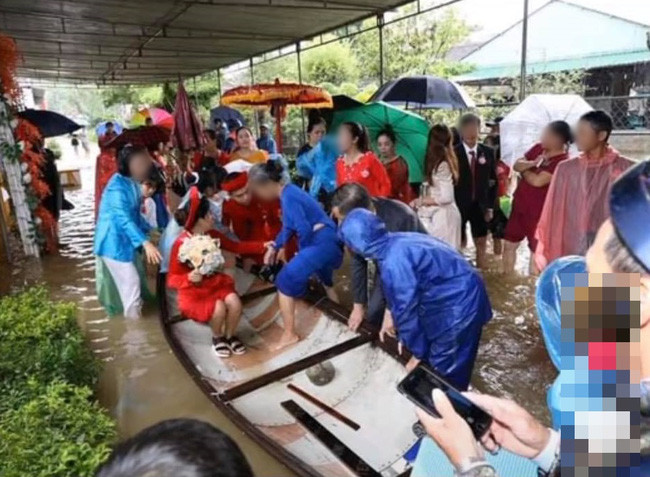 Cô dâu vén váy, lội bập bõm trong dòng nước lũ. Thấy máy quay, cô vẫn thoải mái đưa ngón tay lên đùa giỡn.