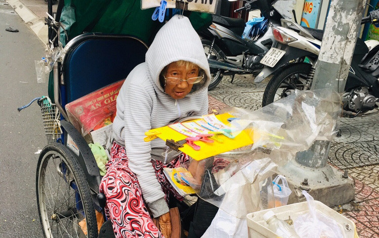 Cụ bà bán vé số ven đường Điện Biên Phủ, quận 10 trùm kín áo len vì lạnh bất thường ở TP HCM trong những ngày đầu năm 2019.