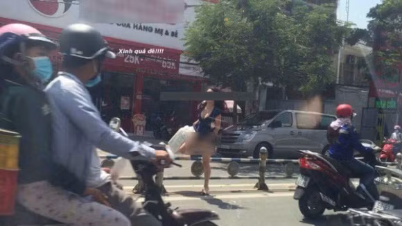 Diện chiếc váy ngắn khoét sâu cổ để lộ gần trọn vòng 1, quý cô Việt trong ảnh còn gây choáng váng hơn khi không mặc quần "chíp" mà vẫn thản nhiên tốc váy để bước qua giải phân cách, làm lộ rõ "vùng nhạy cảm". Ảnh tổng hợp từ Facebook.