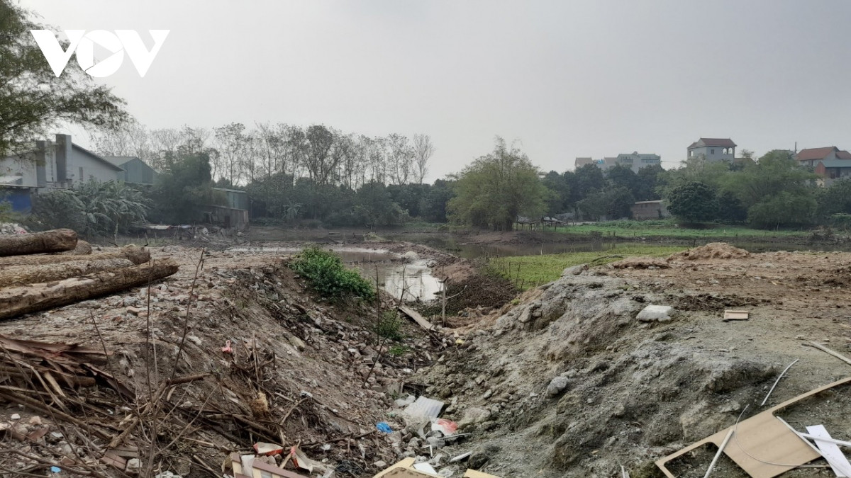 Đằng sau hàng rào tôn, một khu ruộng đang mất dần.