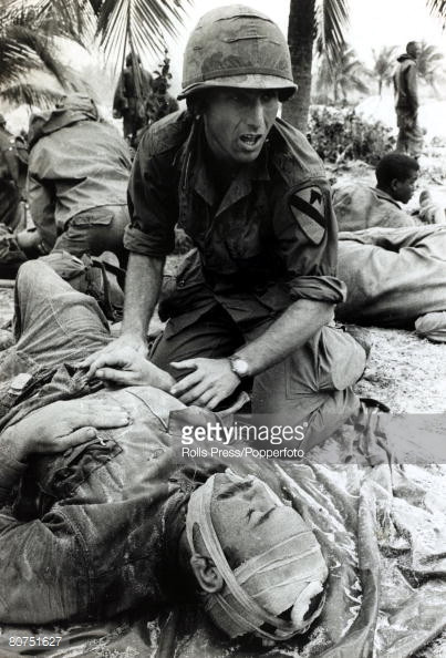 Bác sĩ quân y Mỹ gọi cáng thương trong lúc sơ cứu cho các binh lính của Sư đoàn Kỵ binh bay số 1 bị thương trong chiến dịch Masher ở Bồng Sơn, Quảng Ngãi, tháng 1/1966. Ảnh: Rolls Press/Popperfoto - Gettyimages.