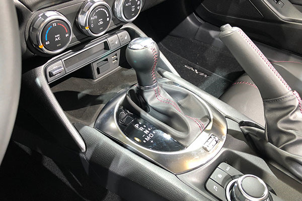 Cần số “giả lập” của Mazda MX-5 Miata: Mazda MX-5 Miata sử dụng hộp số tự động. Tuy nhiên, thiết kế cần số của mẫu xe này sẽ khiến không ít người lầm tưởng với chiếc cần chuyển số trên những chiếc xe số sàn thế hệ cũ. Cần số của MX-5 Miata được tạo hình khá cổ điển với kiểu trục dọc, đầu trên dạng tròn, đường chỉ đỏ nổi bật cùng lớp da bọc xung quanh.