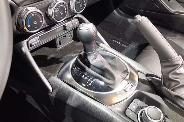 Cần số “giả lập” của Mazda MX-5 Miata: Mazda MX-5 Miata sử dụng hộp số tự động. Tuy nhiên, thiết kế cần số của mẫu xe này sẽ khiến không ít người lầm tưởng với chiếc cần chuyển số trên những chiếc xe số sàn thế hệ cũ. Cần số của MX-5 Miata được tạo hình khá cổ điển với kiểu trục dọc, đầu trên dạng tròn, đường chỉ đỏ nổi bật cùng lớp da bọc xung quanh.