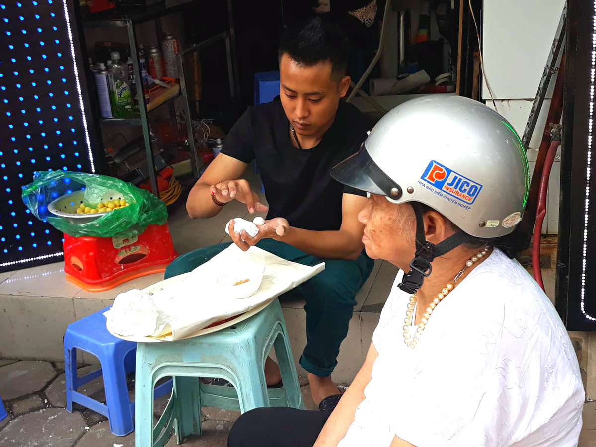 Một cụ bà ngồi đợi người nhà xếp hàng để lấy bánh.