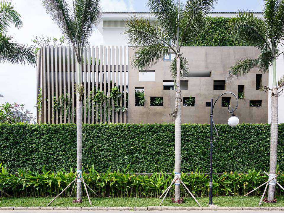 Bức tường rào bê tông thiết kế nhiều khoảng hở, giúp thông gió. Kế đến là hàng rào cây xanh được cắt tỉa gọn gàng.