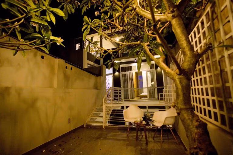 Một bộ bàn ghế nhỏ đặt dưới tán cây hoa rực rỡ trở thành nơi thư giãn lý tưởng cho gia đình.