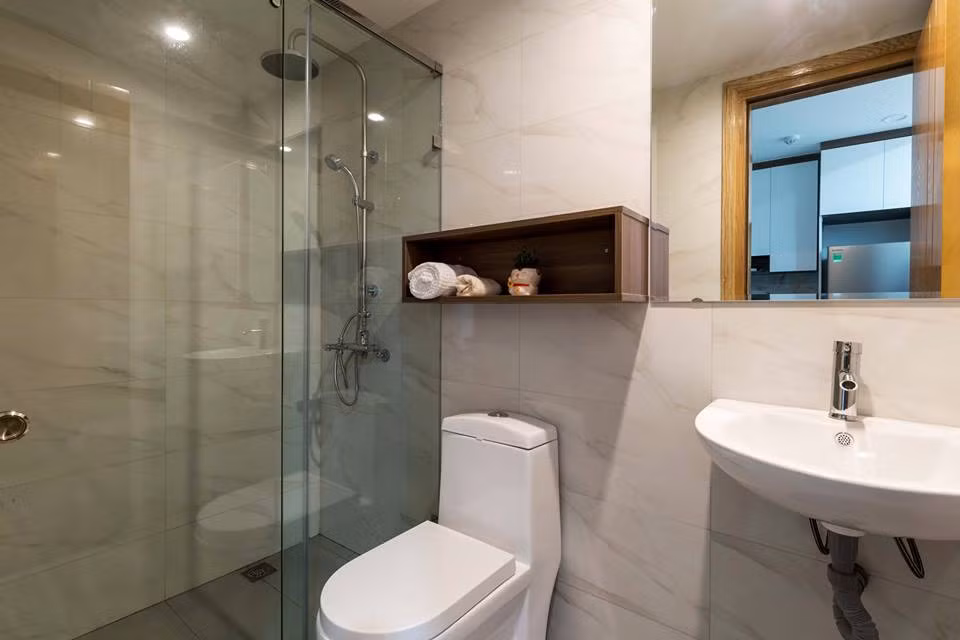 Vách kính giúp ngăn cách khu vực ướt và khu vực khô trong phòng tắm. Tường được ốp gạch men có độ trơn bóng đẹp mắt.
