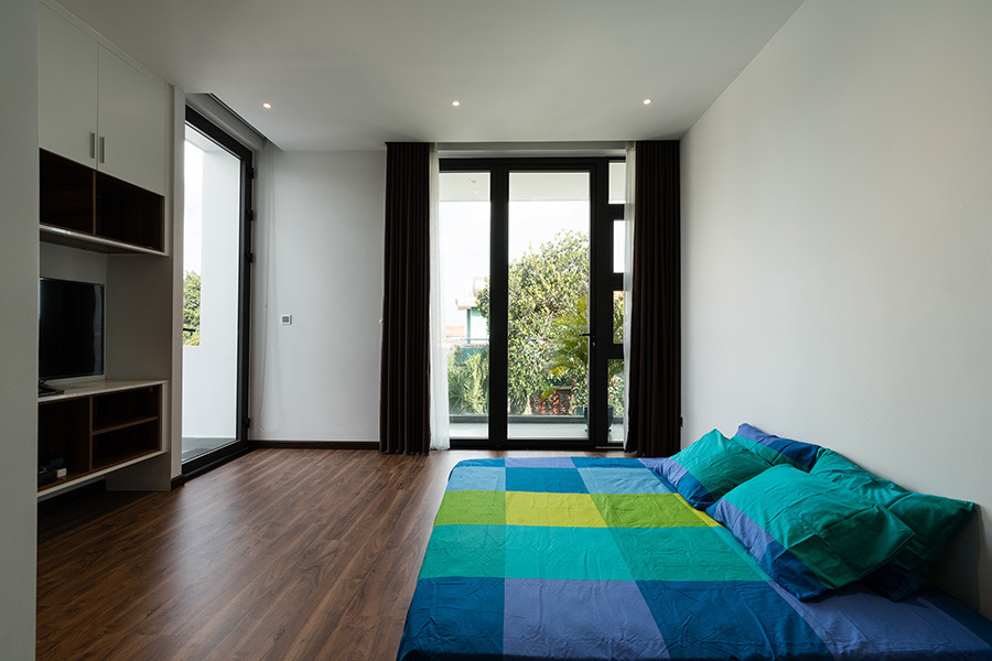 Gam màu trắng kết hợp với các khung cửa kính lớn đón ánh sáng và gió khiến không gian phòng ngủ rộng thoáng hơn.