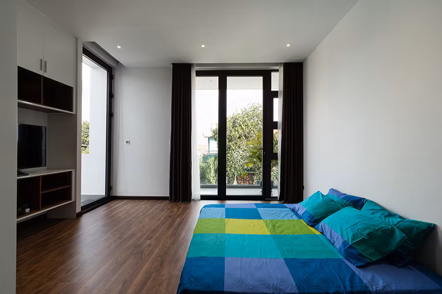 Gam màu trắng kết hợp với các khung cửa kính lớn đón ánh sáng và gió khiến không gian phòng ngủ rộng thoáng hơn.