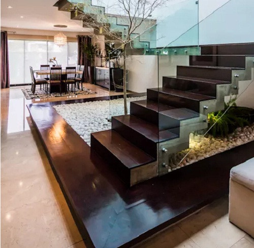 Cầu thang gỗ lan can bằng kính không chỉ tạo thẩm mỹ mà còn giúp ánh sáng tự nhiên trải khắp nhà. Ảnh: Aaestudio.