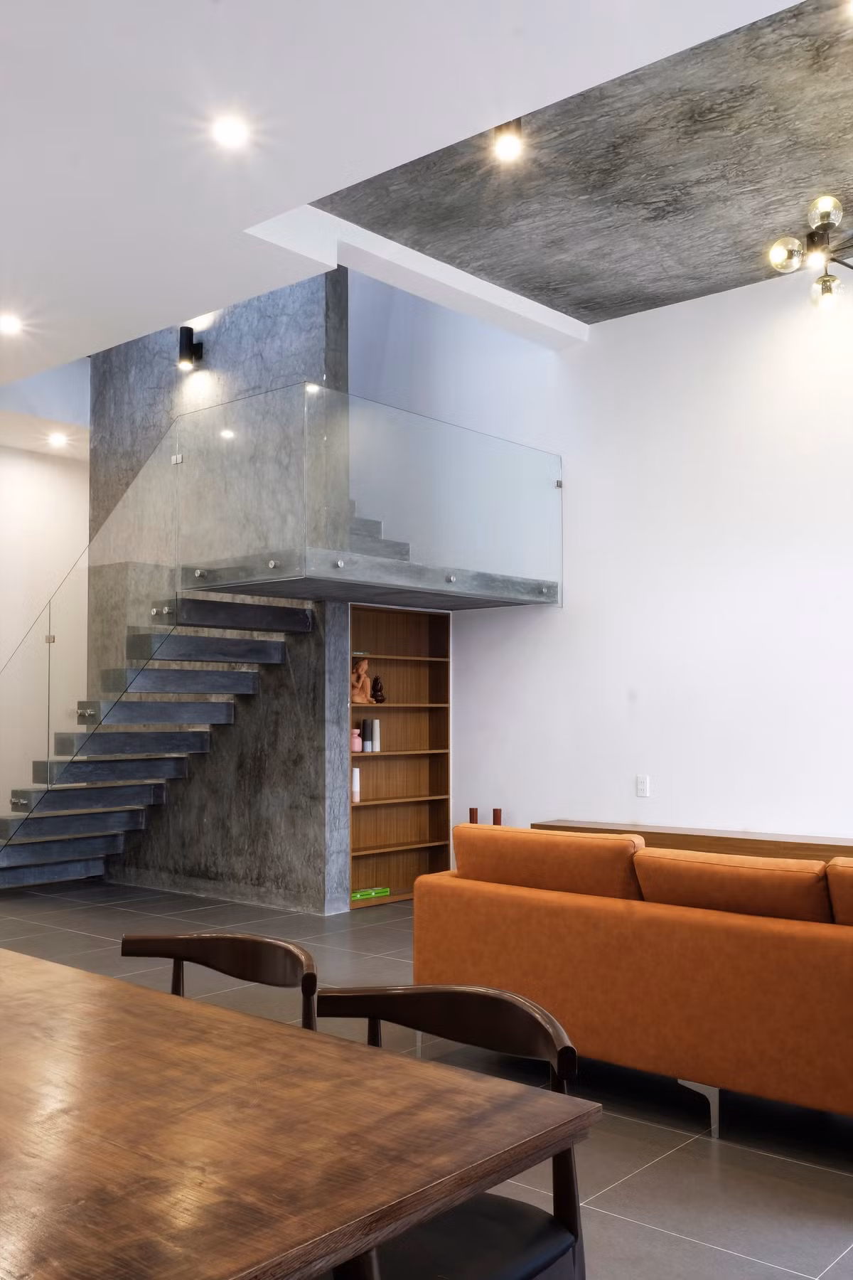 Ở tầng 1, cầu thang bê tông sử dụng lan can kính như nới rộng không gian.