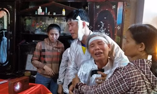 Anh Hoàng và mẹ chết lặng trước quan tài của vợ. Ảnh: H.Thạch.