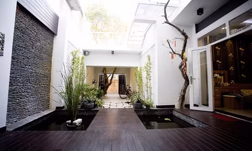 Lối vào nhà ống thông qua một khoảng giếng trời rộng, hai bên bố trí hồ cá nhỏ tạo khoảng đệm tươi mát cho không gian bên trong.