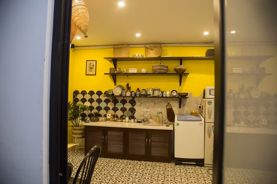 Kệ tủ gỗ mở xưa cũ đặt cạnh máy giặt, lò vi sóng, tủ lạnh.