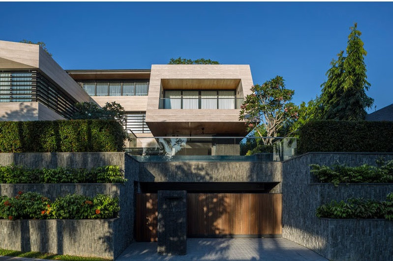 Mặt tiền biệt thự 2 tầng trang trí bằng lớp đá vôi màu xám bạc tương phản với lớp đá màu đen. Hai khối riêng biệt được kết nối bởi khoảng lưu thông trung tâm.