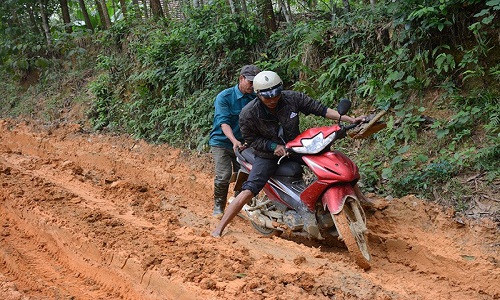 Một chiếc xe máy bị mắc lầy hơn nửa bánh xe, phải nhờ người giúp