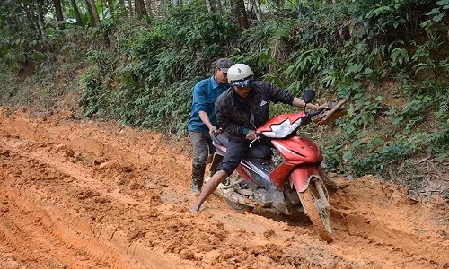 Một chiếc xe máy bị mắc lầy hơn nửa bánh xe, phải nhờ người giúp