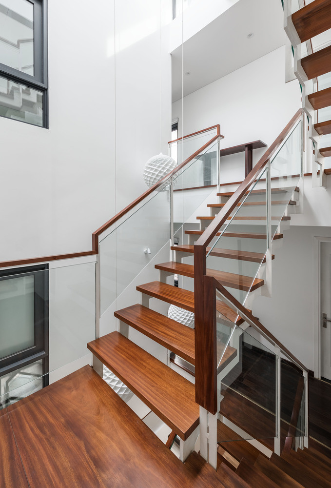 Cầu thang gỗ sử dụng lan can kính hiện đại.