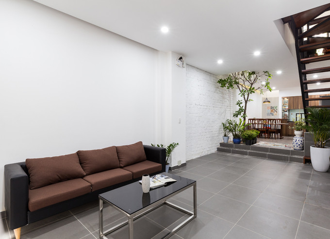 Phòng khách giản dị với sofa màu nâu cùng bàn trà kim loại mặt kính.