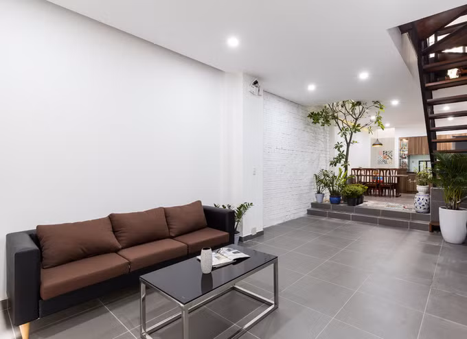 Phòng khách giản dị với sofa màu nâu cùng bàn trà kim loại mặt kính.