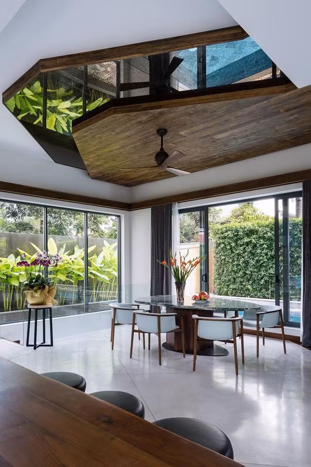 Bàn ăn mặt đá kê gần tường kính nhìn ra hồ bơi.