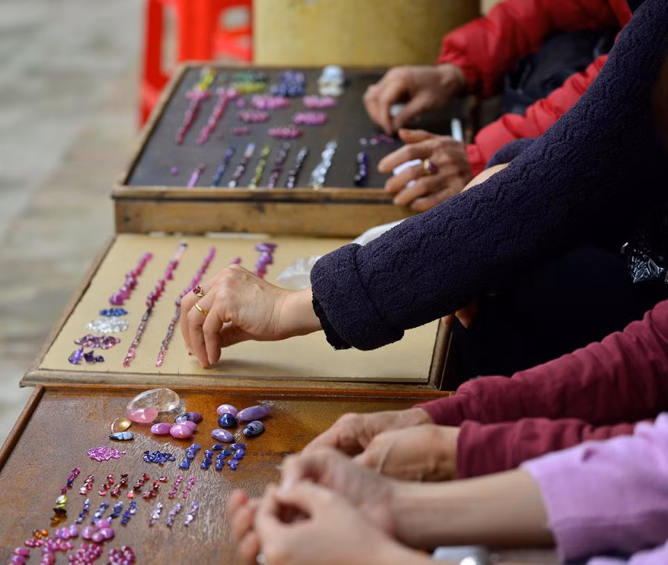 Chủ gian hàng lấy sản phẩm đá đã chế tác sẵn hoặc đá sơ chế thô rồi bày biện trên bàn gỗ theo từng loại. Ảnh: Zing.