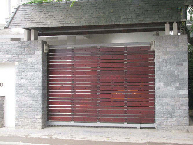 Mái hiên vừa là điểm nhấn, vừa có tác dụng bảo vệ, che chắn nắng mưa cho cánh cổng gỗ tự nhiên, giúp nâng cao tuổi thọ. Ảnh: Skyhome.