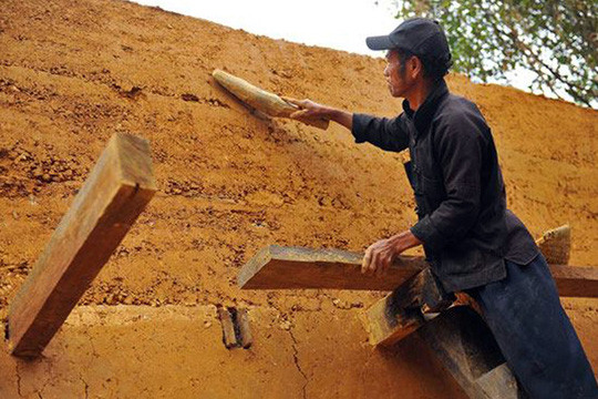 Bức trình tường trong ngôi nhà của người Mông làm hoàn toàn bằng đất nện dày, loại đất có độ kết dính cao, loại bỏ sạch rễ cây, đá to, cỏ rác. Ảnh: NLĐ.