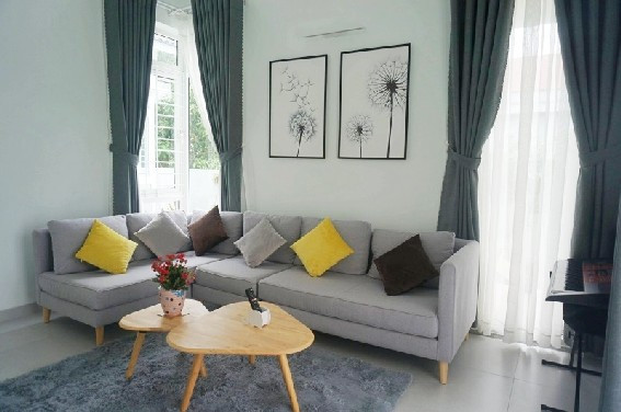 Sofa đơn giản, thảm trải sàn và bộ rèm cửa với màu xám nổi bật trên gam trắng của tường và sàn mang đến không gian ấm cúng và hiện đại.