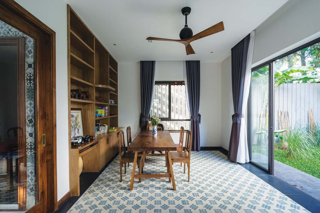 Phòng làm việc sử dụng kệ lưu trữ và bàn ghế sáng màu. Cửa kính lớn cho tầm nhìn thoáng mát ra khu vườn bên ngoài.