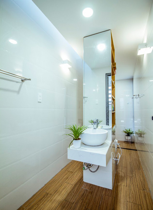 Nhà vệ sinh thoáng mát với sắc trắng và nội thất gỗ chủ đạo.
